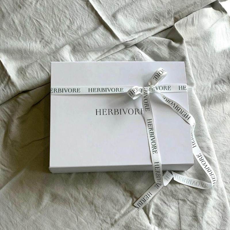 Presentation box filled with fresh fruit tied off in a Herbivore ribbon