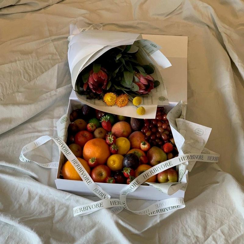 Presentation box filled with fresh fruit tied off in a Herbivore ribbon