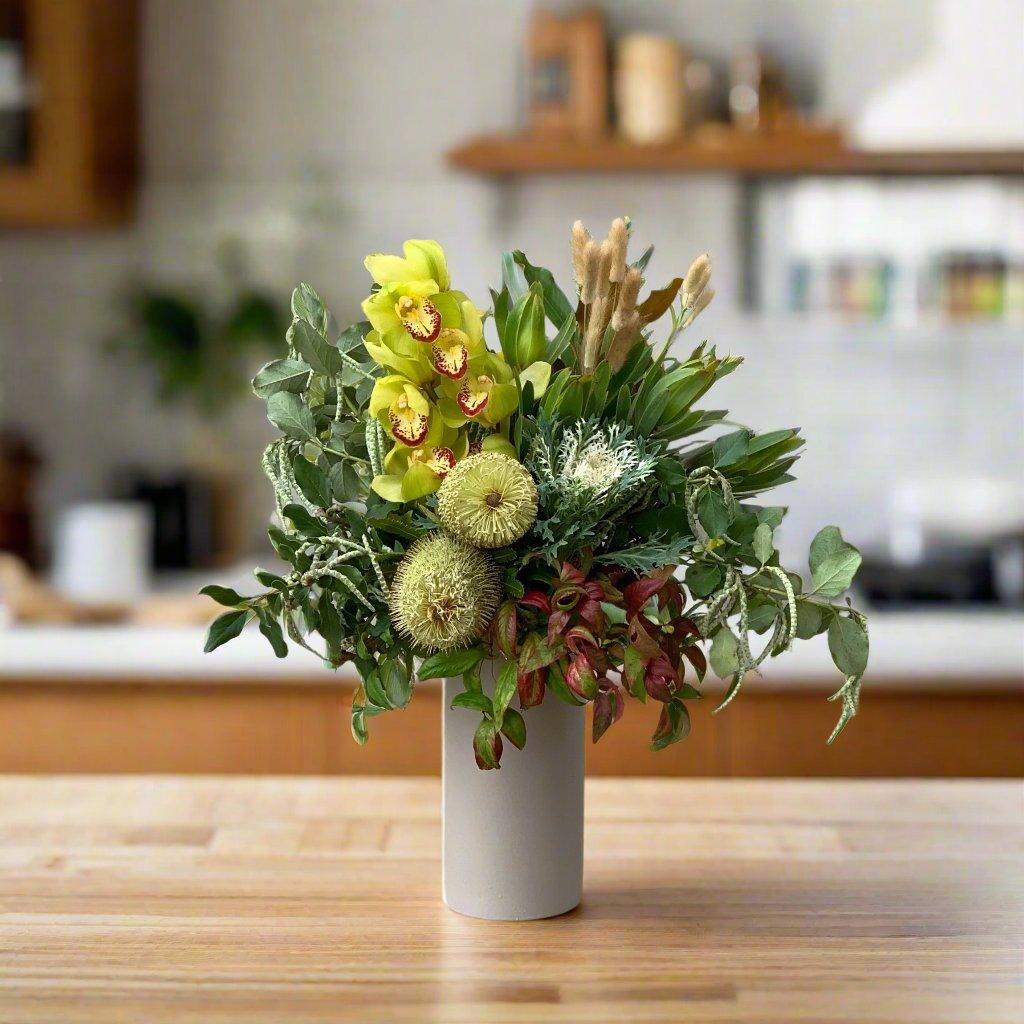 Florist arrangement with native flowers like banksias in a light grey vase