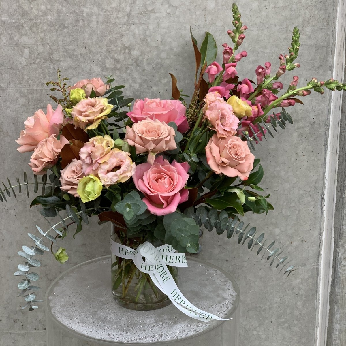 Small pastel arrangement with pink roses and green foliage 