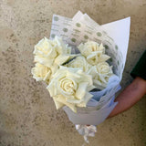 Small bunch of white roses wrapped in Herbivore's signature floral wrapping paper