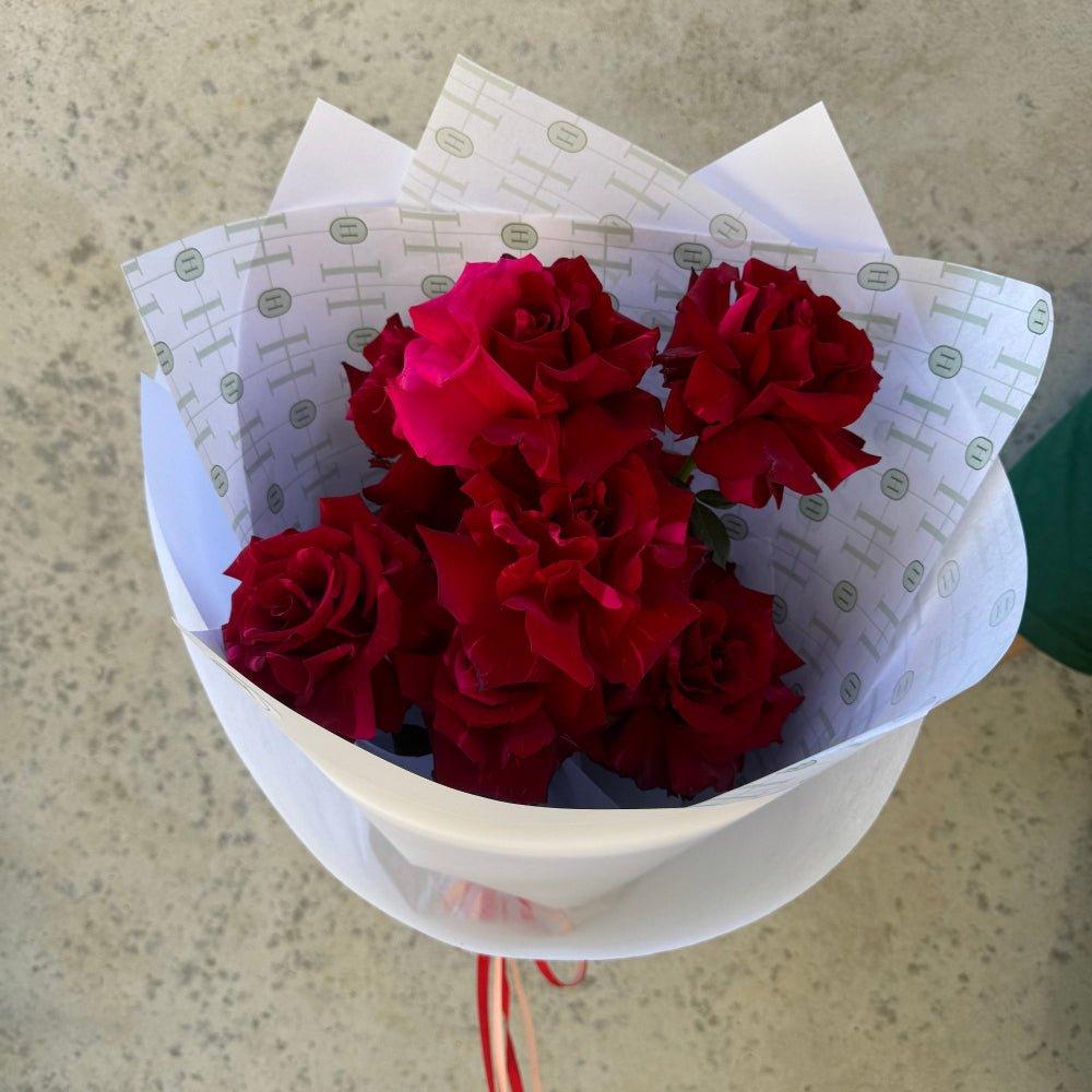 Small bunch of red roses rapped in white paper