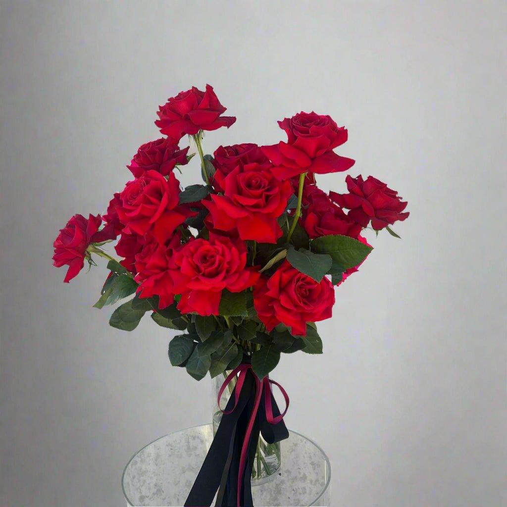 Large bunch of a dozen red roses tied in a bouquet for Valentines Day